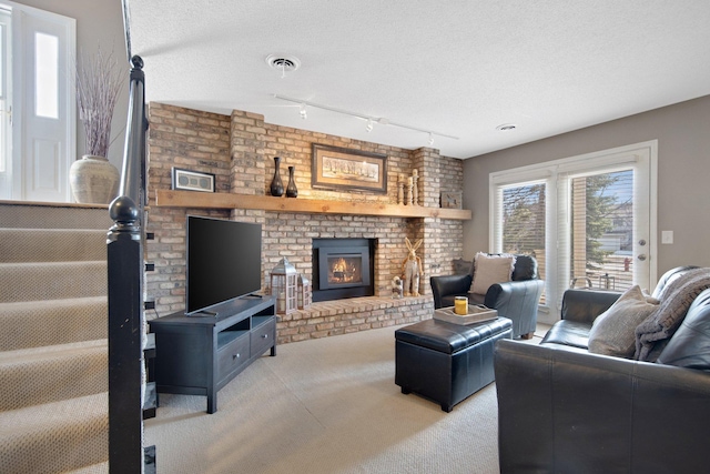 living room featuring a brick fireplace, visible vents, carpet floors, and a textured ceiling