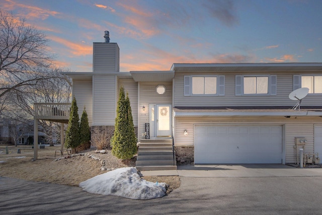 view of front of property featuring concrete driveway, an attached garage, and a chimney