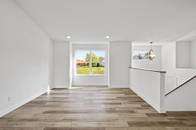 spare room featuring a chandelier, recessed lighting, baseboards, and wood finished floors