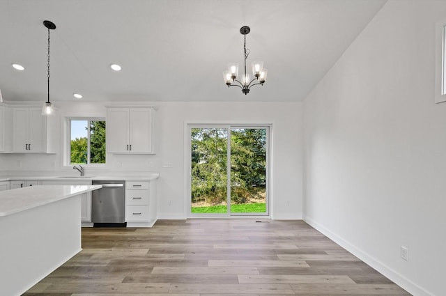 kitchen featuring stainless steel dishwasher, light wood-style flooring, white cabinets, and light countertops