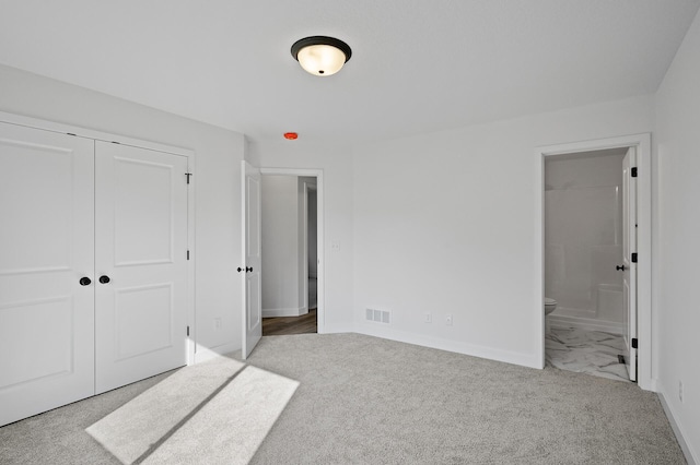 unfurnished bedroom featuring visible vents, baseboards, carpet floors, ensuite bathroom, and a closet