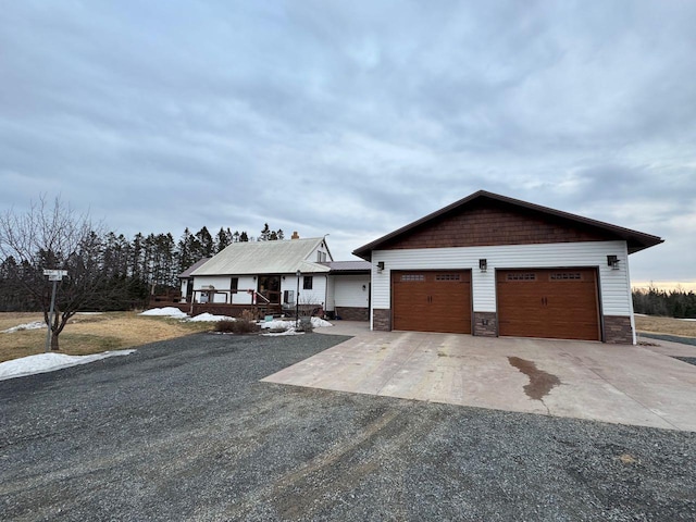 view of front of home with stone siding, a porch, concrete driveway, and an attached garage