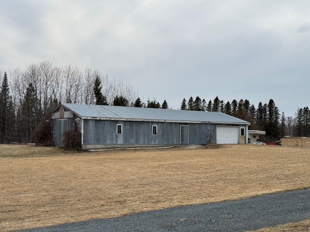 view of front of house featuring a garage, metal roof, and a front lawn