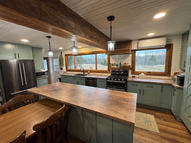 kitchen with range with gas cooktop, a wall unit AC, high end fridge, and green cabinets