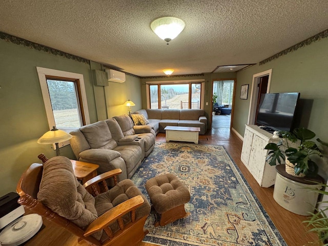 living area with a textured ceiling, an AC wall unit, and wood finished floors