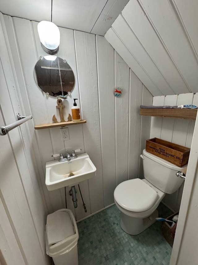 half bath featuring vaulted ceiling, toilet, and a sink