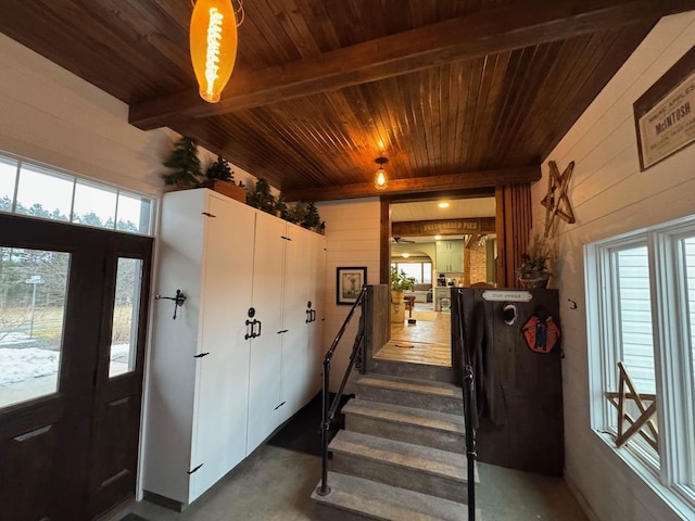 foyer featuring beam ceiling, wooden walls, concrete floors, and wooden ceiling