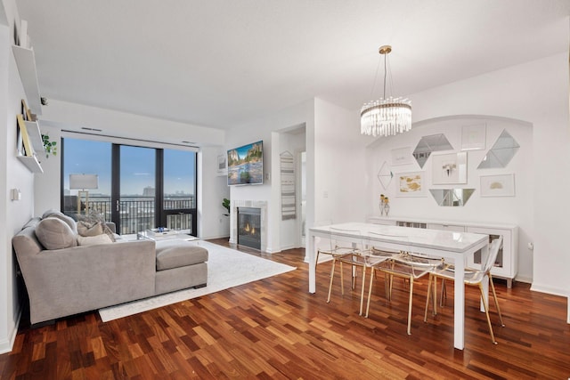 living room with a glass covered fireplace, a chandelier, baseboards, and wood finished floors