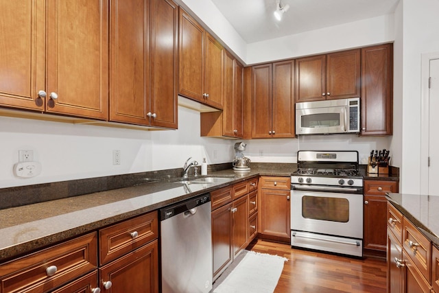 500 Grant St Unit 807, Minneapolis, MN 55404 - kitchen featuring dark stone countertops, a sink, dark wood-type flooring, appliances with stainless steel finishes, and brown cabinets