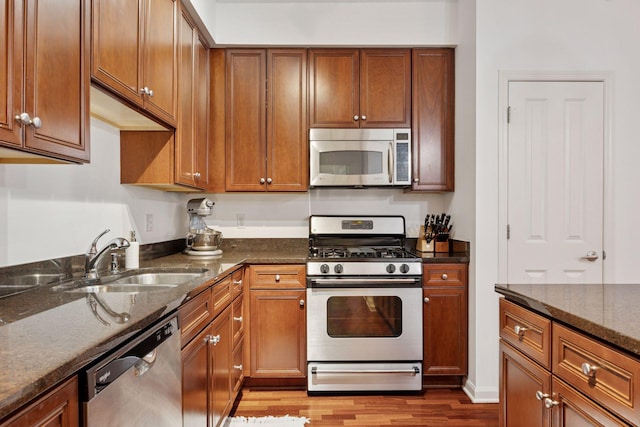 500 Grant St Unit 807, Minneapolis, MN 55404 - kitchen featuring dark stone counters, appliances with stainless steel finishes, wood finished floors, brown cabinetry, and a sink