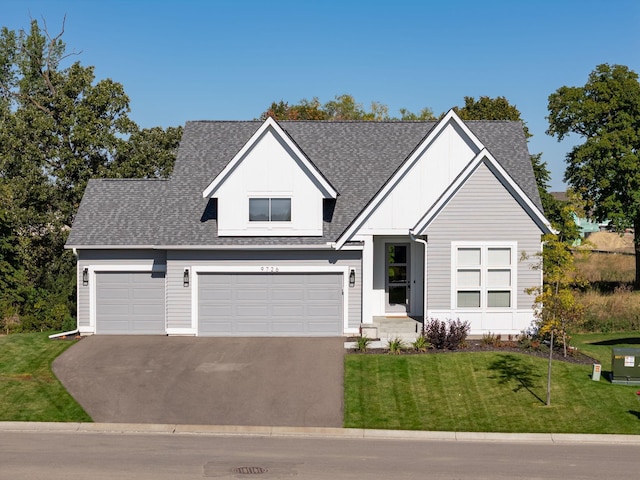 view of front of home featuring a garage, driveway, roof with shingles, and a front yard