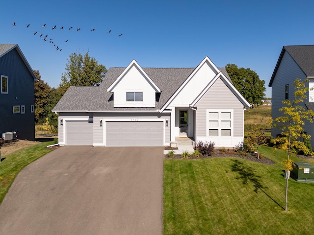 view of front of property with aphalt driveway, a garage, a shingled roof, and a front yard