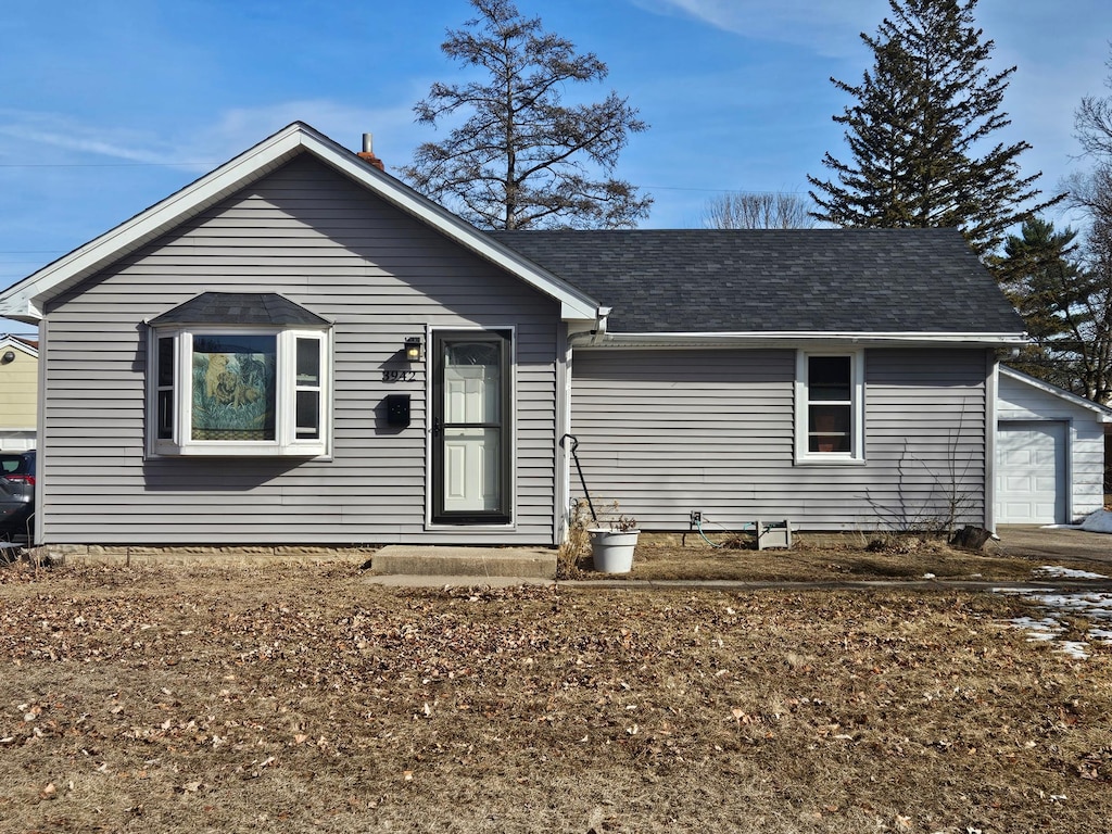 ranch-style house with an outdoor structure, a garage, and a shingled roof