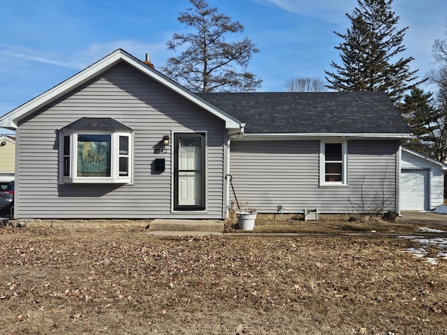 ranch-style house with an outdoor structure, a garage, and a shingled roof