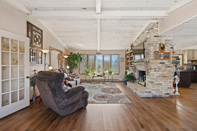 living area featuring lofted ceiling with beams, wood finished floors, wooden ceiling, and a fireplace