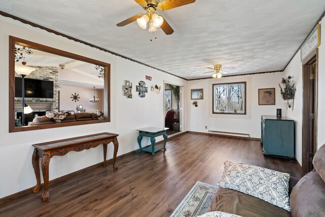 living area featuring a ceiling fan, wood finished floors, baseboards, a baseboard radiator, and vaulted ceiling