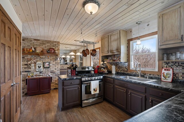 kitchen featuring dark countertops, stainless steel range with gas stovetop, brick wall, and a sink