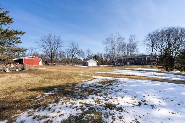 yard covered in snow featuring a garage, an outbuilding, and a pole building