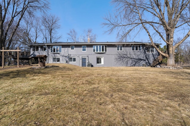 rear view of property featuring stairs and a yard