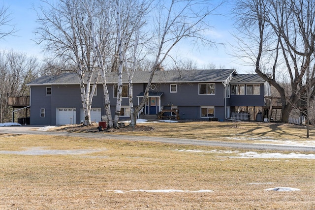 split foyer home with a front yard, a sunroom, an attached garage, and driveway