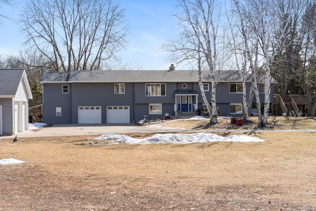 bi-level home featuring an attached garage, a chimney, and driveway