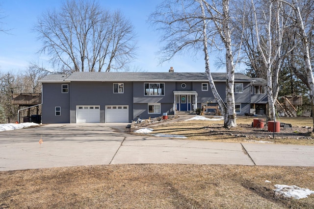 split foyer home with concrete driveway, a garage, and a chimney