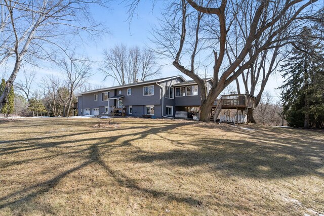 rear view of property with a yard, a deck, and an attached garage