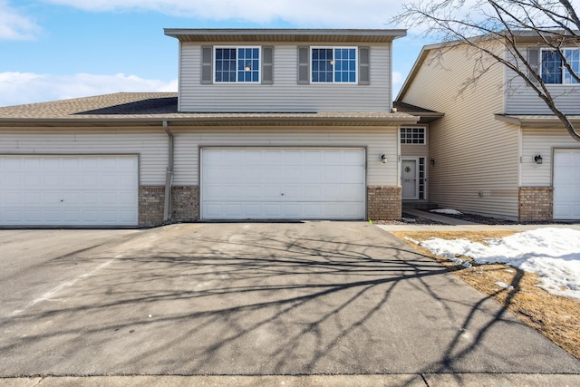 view of front of property with brick siding, roof with shingles, and driveway