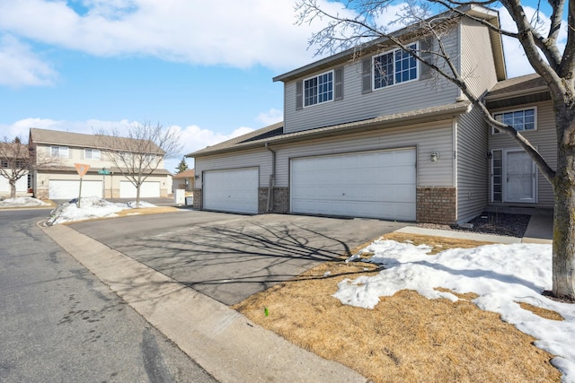 view of front facade featuring aphalt driveway, brick siding, and a garage