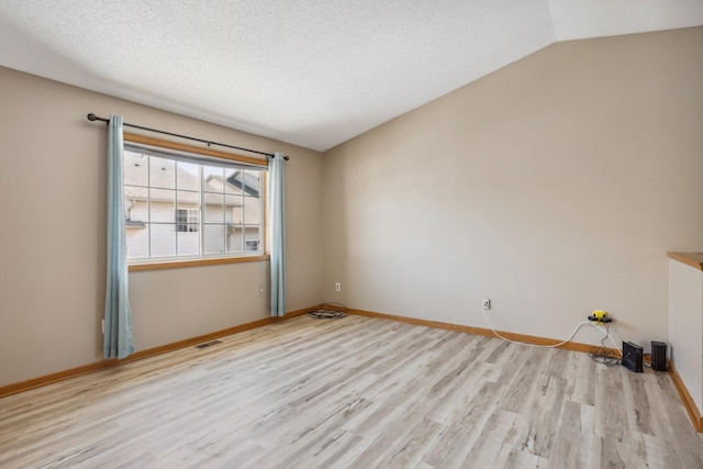 unfurnished room featuring visible vents, baseboards, lofted ceiling, wood finished floors, and a textured ceiling