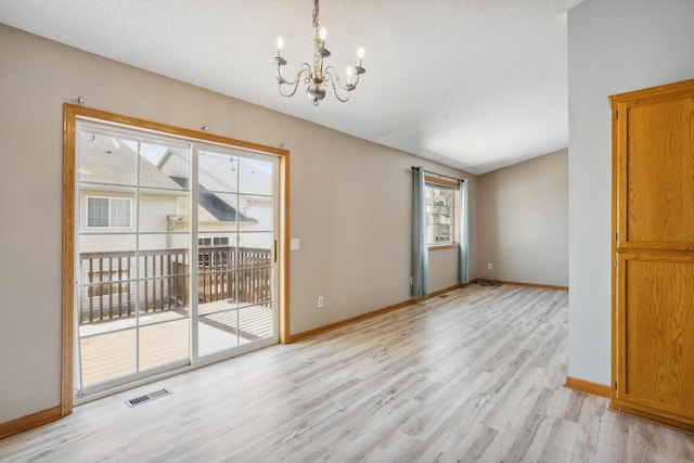 empty room with light wood-type flooring, visible vents, baseboards, and a chandelier