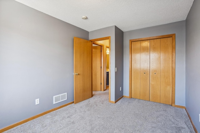 unfurnished bedroom with baseboards, carpet floors, visible vents, a closet, and a textured ceiling