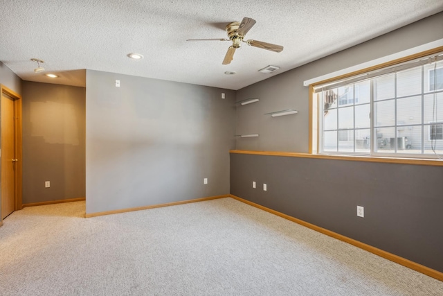 empty room with a ceiling fan, baseboards, carpet floors, and a textured ceiling