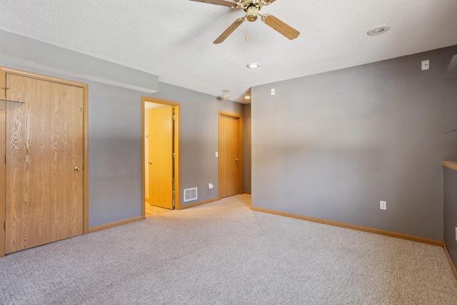 unfurnished bedroom featuring visible vents, a textured ceiling, carpet, and baseboards