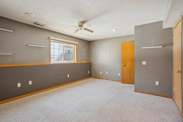 empty room with carpet, baseboards, visible vents, ceiling fan, and a textured ceiling