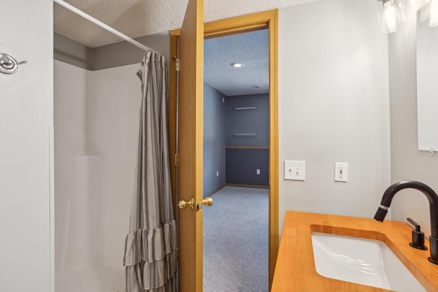 bathroom with a textured ceiling, a shower with shower curtain, baseboards, and a sink