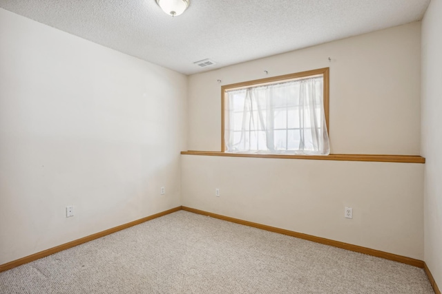 carpeted empty room with visible vents, baseboards, and a textured ceiling