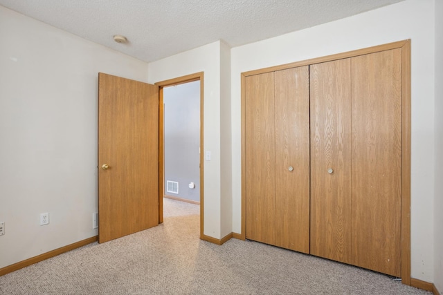 unfurnished bedroom featuring visible vents, a textured ceiling, a closet, carpet floors, and baseboards