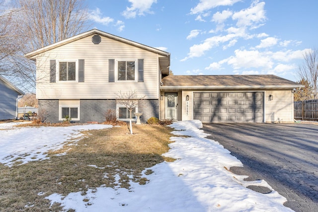 tri-level home with driveway, a garage, and fence