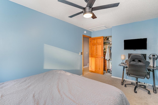 carpeted bedroom featuring a textured ceiling, a closet, baseboards, attic access, and ceiling fan