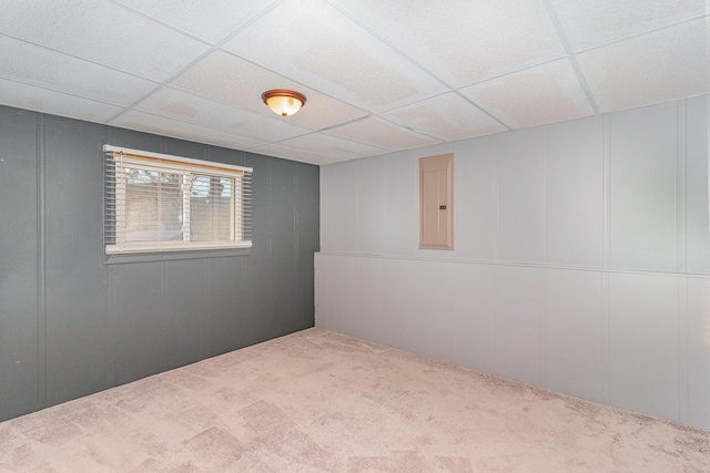 empty room with electric panel, a paneled ceiling, carpet floors, and a decorative wall