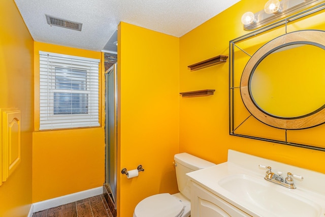 bathroom featuring visible vents, toilet, a textured ceiling, and a shower stall