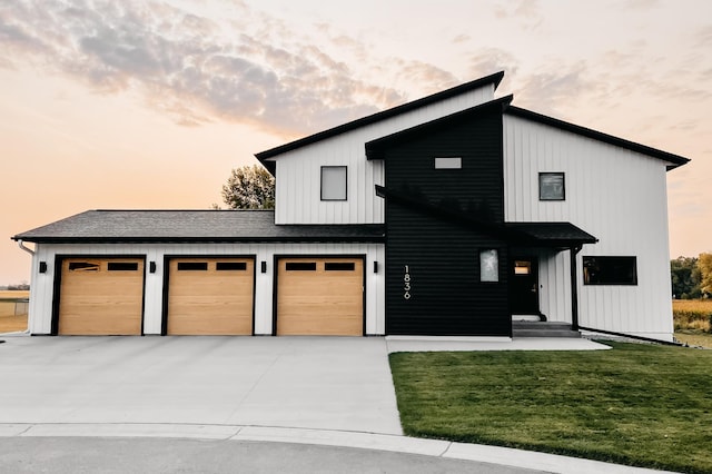 modern inspired farmhouse featuring board and batten siding, a front lawn, concrete driveway, roof with shingles, and a garage