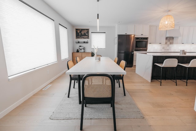 dining space with visible vents, light wood-style flooring, and baseboards