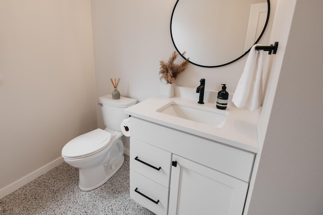 bathroom featuring toilet, vanity, speckled floor, and baseboards