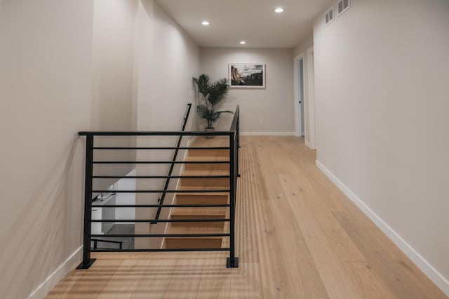 hall featuring visible vents, an upstairs landing, wood finished floors, recessed lighting, and baseboards