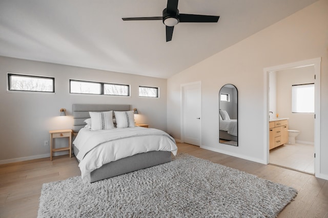 bedroom with light wood finished floors, connected bathroom, baseboards, lofted ceiling, and a ceiling fan