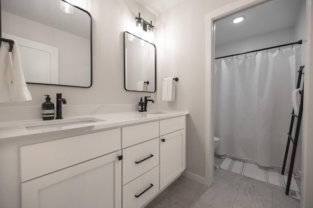 bathroom with tile patterned flooring, double vanity, toilet, and a sink