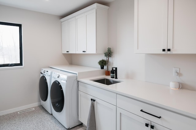 laundry room featuring visible vents, a sink, baseboards, cabinet space, and separate washer and dryer