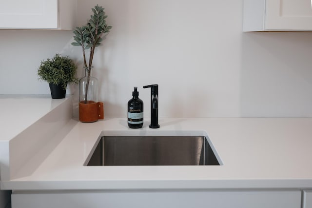 room details featuring light countertops, white cabinets, and a sink